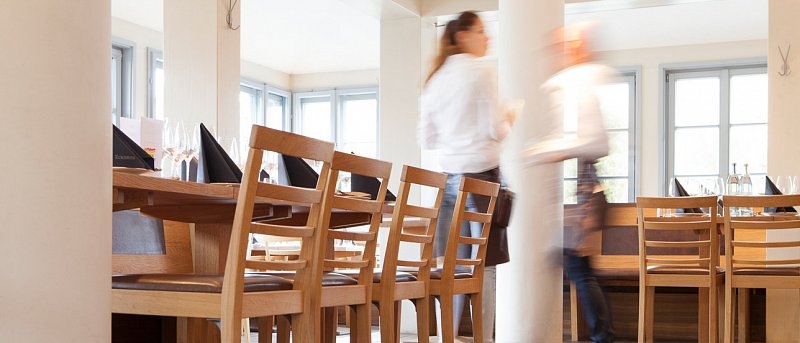 Zwei Servicekräfte laufen durch die Stube mit gedeckten Tischen im Eckerts Wirtshaus in Bamberg